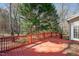 Red wooden deck overlooking a wooded backyard, with some fall leaves at 2412 Mollynick Lane Ln, Wake Forest, NC 27587
