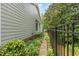 Side yard with an iron fence, stone walkway, rock landscaping and garden areas at 2617 Cottage Cir, Raleigh, NC 27613