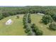 Stunning aerial view of a sprawling estate with a long driveway, white barn, and lush green pastures at 313 Shetland Rd, Rougemont, NC 27572