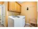 Laundry room features modern white washer and dryer, wood cabinets, and tile flooring at 313 Shetland Rd, Rougemont, NC 27572