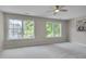 Spacious bedroom with neutral carpeting, a ceiling fan, and large windows offering a view of greenery at 314 Virens Dr, Cary, NC 27511