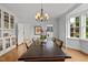 Elegant dining room featuring a long table, chandelier, and built-in display cabinet, complemented by natural light at 3816 Dover Rd, Durham, NC 27707