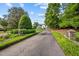 Long driveway leading to a grand white house with lush landscaping and mature trees at 3816 Dover Rd, Durham, NC 27707