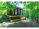 Screened-in porch with lattice base nestled among the trees and stone foundation at 382 Valley Ln, Pittsboro, NC 27312