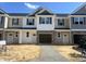 Townhome featuring stone accents, neutral siding, black shutters, and a two-car garage at 3920 Well Fleet Dr, Fuquay Varina, NC 27526