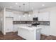 Modern white kitchen featuring an island, stainless steel appliances, and stylish backsplash at 3920 Well Fleet Dr, Fuquay Varina, NC 27526