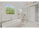 Sleek bathroom features a freestanding tub, glass shower, marble tile, and natural light at 5308 Montclair Dr, Raleigh, NC 27609