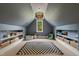 Lofted bonus room with built-in shelving, large window, and a checkered rug. Ideal for a playroom at 5308 Montclair Dr, Raleigh, NC 27609