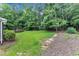 Secluded backyard featuring lush green grass, mature trees, a deck, and a shed at 5521 Erinvale Ct, Holly Springs, NC 27540