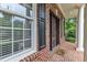 Charming brick front porch featuring a decorative storm door, sidelight windows, and lush green landscaping at 5521 Erinvale Ct, Holly Springs, NC 27540