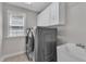 Well-lit laundry room featuring modern machines, overhead cabinets, and a utility sink at 5521 Erinvale Ct, Holly Springs, NC 27540