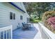 Back deck featuring wood flooring, white railing, table and chairs, as well as blue retractable awning at 5625 Church Rd, Graham, NC 27253