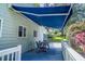 Back deck featuring wood flooring, white railing, table and chairs, as well as blue retractable awning at 5625 Church Rd, Graham, NC 27253