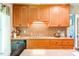 Kitchen featuring a stainless-steel dishwasher, decorative backsplash, and wood cabinets with modern fixtures at 5625 Church Rd, Graham, NC 27253
