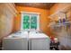 Bright laundry room with washer, dryer, overhead storage, window, and tongue and groove wall decor at 5625 Church Rd, Graham, NC 27253