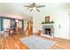 Open concept living room featuring a fireplace, ceiling fan, hardwood floors, and view into the dining area at 5625 Church Rd, Graham, NC 27253