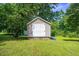 Storage shed with double doors and a blue kayak resting nearby adds practicality and convenience at 5625 Church Rd, Graham, NC 27253