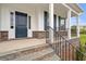 Charming front porch with stone accents, a black metal railing, and a dark blue front door at 60 Bold Dr, Youngsville, NC 27596