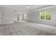 Bright main bedroom showcasing a tray ceiling, plush carpeting, and three windows for natural light at 60 Bold Dr, Youngsville, NC 27596