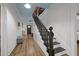 Hallway featuring a staircase, painted blue ceiling, white walls, and wood floors at 6447 Beulah Church Rd, Liberty, NC 27298