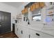 Kitchen features white cabinetry, a farm sink, a window with curtains, and a black door with decor at 6447 Beulah Church Rd, Liberty, NC 27298
