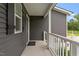 Side porch with sleek gray siding, white railing, and lush greenery at 852 Cokesbury Park Lane Ln, Fuquay Varina, NC 27526
