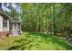 Backyard view with stairs to a screened-in porch and a spacious lawn surrounded by mature trees at 8840 Woodyhill Rd, Raleigh, NC 27613