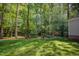 Lush backyard with mature trees and a fire pit area featuring Adirondack chairs for cozy evenings at 8840 Woodyhill Rd, Raleigh, NC 27613