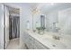 Bathroom featuring double sink vanity, updated lighting, and walk-in shower with neutral tiling at 8840 Woodyhill Rd, Raleigh, NC 27613