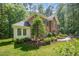Brick home with attached sunroom, mature trees and manicured landscaping at 8840 Woodyhill Rd, Raleigh, NC 27613