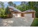 A spacious brick three-car garage with ample parking space and a large driveway, with mature trees in the background at 8840 Woodyhill Rd, Raleigh, NC 27613