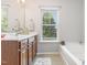 Bright bathroom features a large window, a soaking tub, and a vanity with drawers at 100 Stratford Lakes # 130, Durham, NC 27713