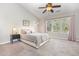 Bright bedroom features a ceiling fan, three windows, and a nightstand with a lamp at 100 Stratford Lakes # 130, Durham, NC 27713