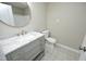 A modern bathroom with a gray vanity with a marble countertop, round mirror, and decorative floor tiles at 1110 Elmira Ave, Durham, NC 27707