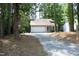 A single-story house nestled amongst the trees has an attached garage and long drive at 1110 Elmira Ave, Durham, NC 27707