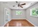 Bedroom with hardwood floors, ceiling fan and light fixture, and view of the outdoors through windows at 112 S Joyland St, Durham, NC 27703