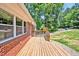 An outside side view of the house with a wood porch, windows, and brick siding with a green and sunny backdrop at 112 S Joyland St, Durham, NC 27703