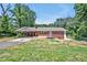 Charming brick home featuring a carport and a wooden porch, surrounded by a partially wooded lot at 112 S Joyland St, Durham, NC 27703