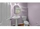 Charming powder room with pedestal sink, oval mirror, and decorative shelves at 1120 Renewal Pl # 111, Raleigh, NC 27603