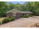 Inviting brick ranch home featuring lush landscaping and a spacious gravel driveway, nestled among mature trees at 1134 Deerfoot Trail Trl, Sanford, NC 27332