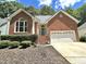 Charming red brick home featuring a well-manicured lawn, two-car garage and arched doorway at 121 Chimney Rise Dr, Cary, NC 27511