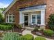 Inviting brick front porch with classic columns, comfortable seating, and beautifully manicured garden at 12221 Orchardgrass Ln, Raleigh, NC 27614