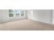 Spacious bedroom featuring neutral carpet, three windows, and a door to a hallway at 123 Pony Gallop Ln, Clayton, NC 27520