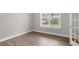 Empty bedroom with hardwood floors, a large window overlooking the backyard, and a door to another room at 123 Pony Gallop Ln, Clayton, NC 27520
