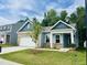 Charming single-Gathering home with a manicured lawn, attached garage, and beautiful blue accents against a bright blue sky at 124 N Keatts Winner Ct, Wilson's Mills, NC 27520