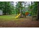 The backyard includes a swing set with a slide and swings, nestled among the trees at 129 Clark Ct, Youngsville, NC 27596