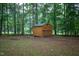 Backyard with a wooded area and a wooden shed with a ramp entrance at 129 Clark Ct, Youngsville, NC 27596