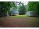 Spacious backyard with lush greenery, featuring a swing set, playset, and storage shed at 129 Clark Ct, Youngsville, NC 27596