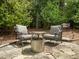 Cozy backyard patio with stone pavers, comfortable seating and a stainless steel fire pit, surrounded by lush greenery at 18 Acornridge Ct, Durham, NC 27707