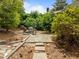 Charming backyard retreat with a stone pathway, seating area, and lush landscaping for outdoor relaxation at 18 Acornridge Ct, Durham, NC 27707